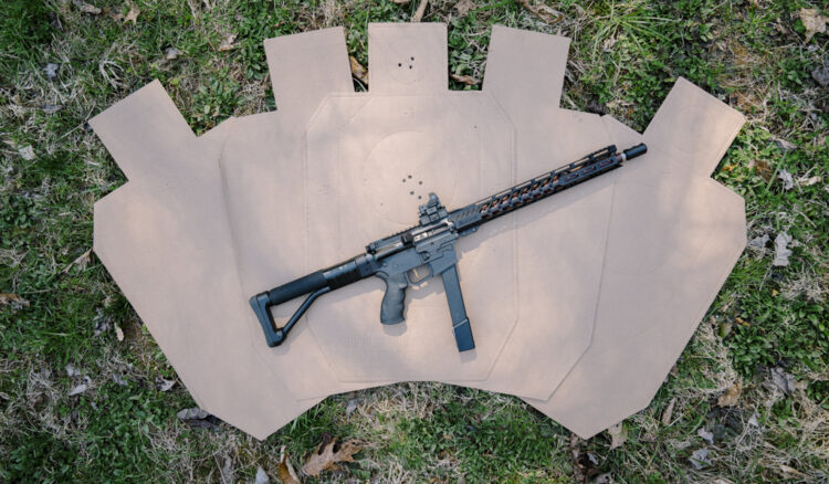 a pistol caliber carbine laying on top of idpa targets