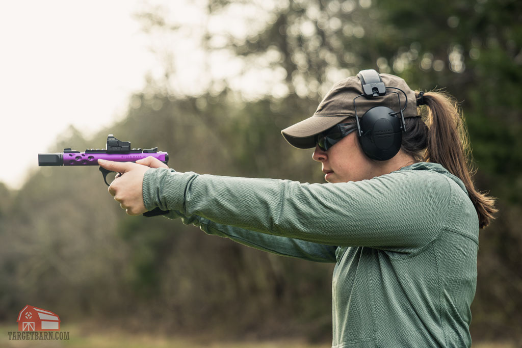 A shooter firing a 22 pistol with a red dot optic at the range