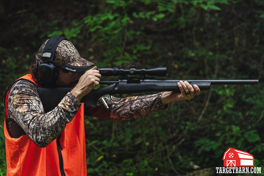 A hunter in blaze orange sighting in a rifle at the range