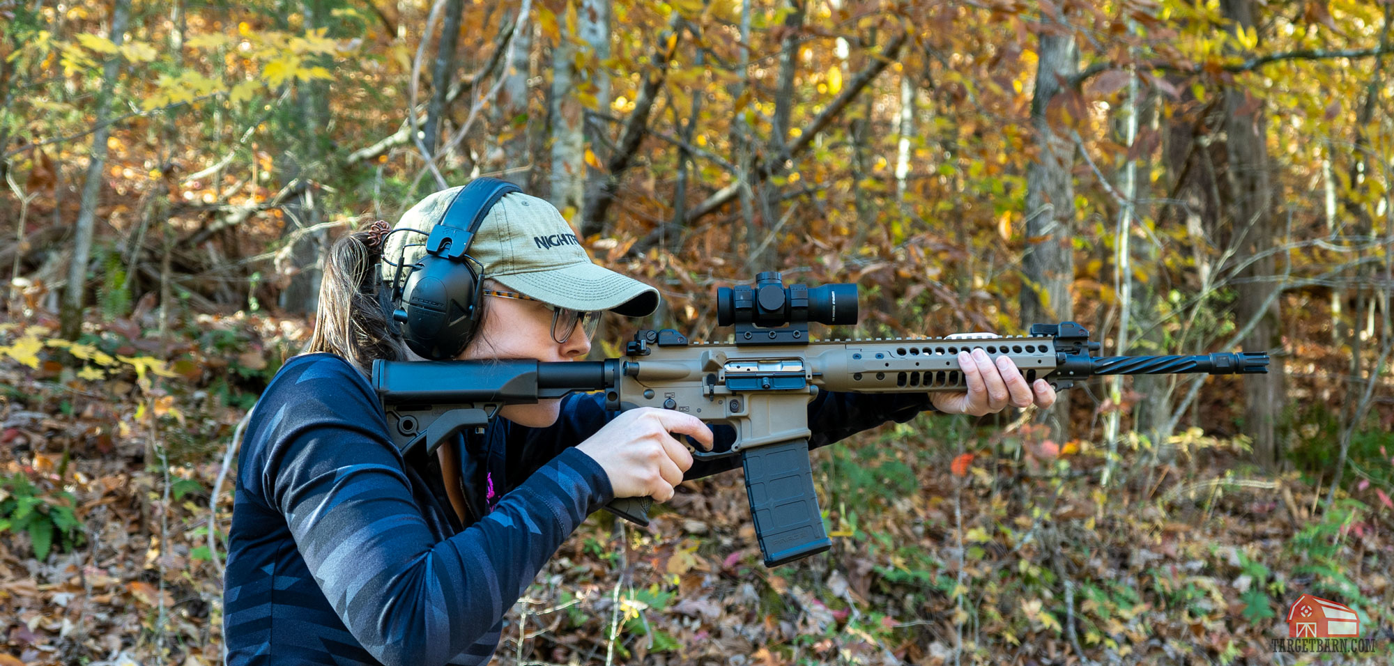 the author wearing a baseball hat while she shoots a rifle at the range to protect her face from hot brass