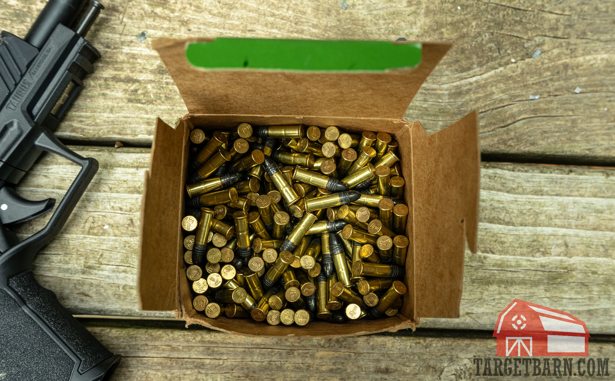 an open box of loose thunderbolt rounds next to a pistol at the gun range