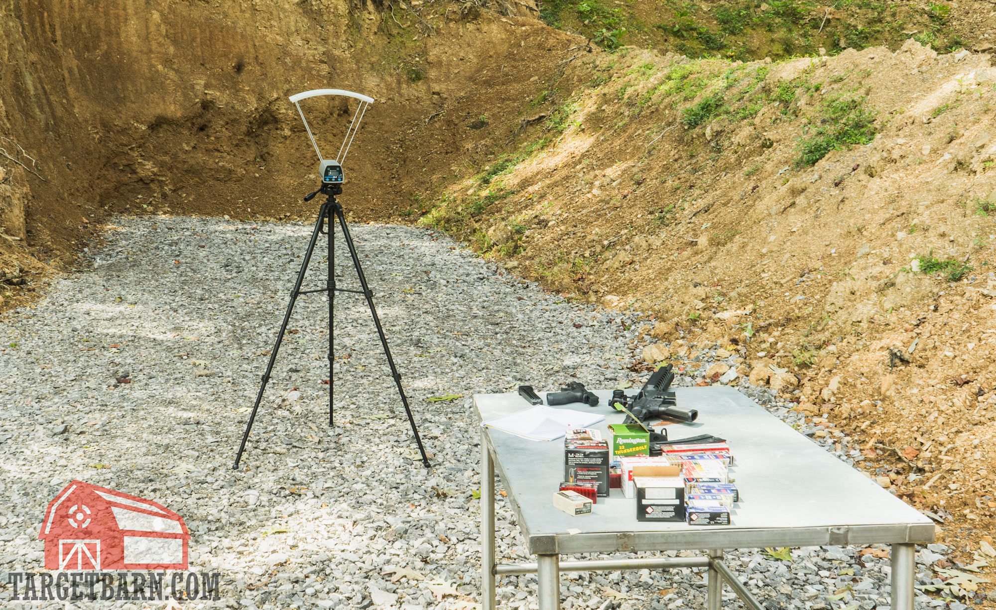 a chronograph set up at the range with a table that has ammo and guns on it