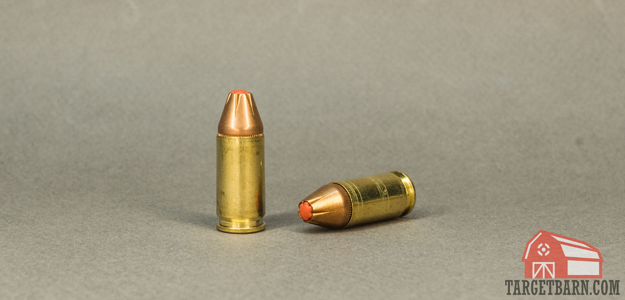two rounds of hornady critical defense 9mm, one standing and one laying on its side to show the round's red tip