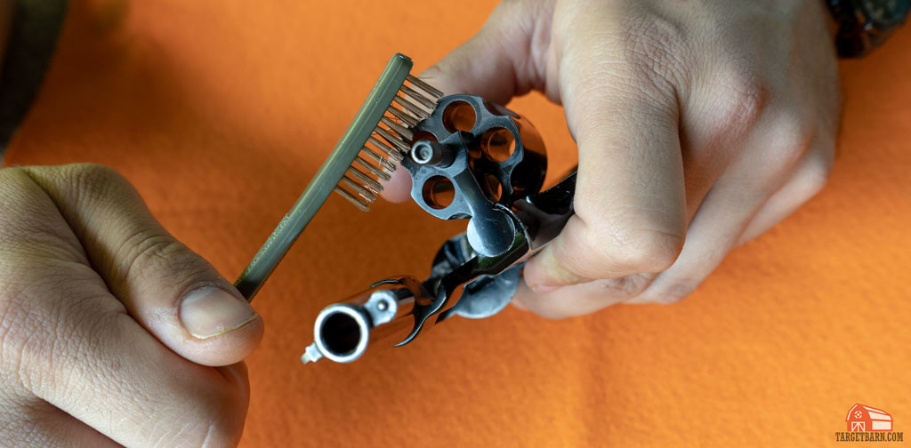 using a bronze brush and cleaner to clean the revolver's cylinder face