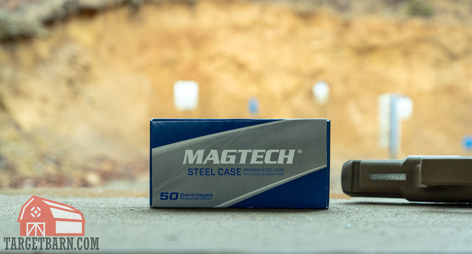 a box of magtech steel case 9mm next to a gun with steel targets in the background