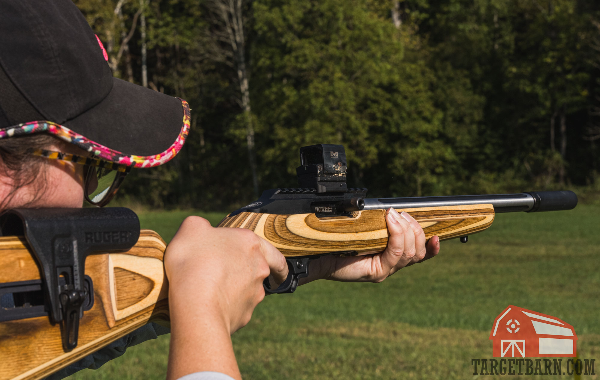 a woman shooting a ruger 10/22 mounted with a suppressor