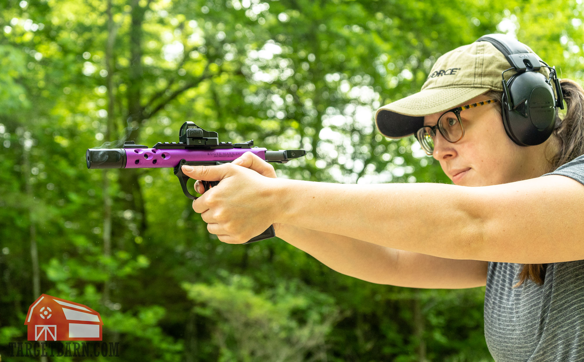 a woman shooting a pistol with a compensator with gases coming out of the compensator