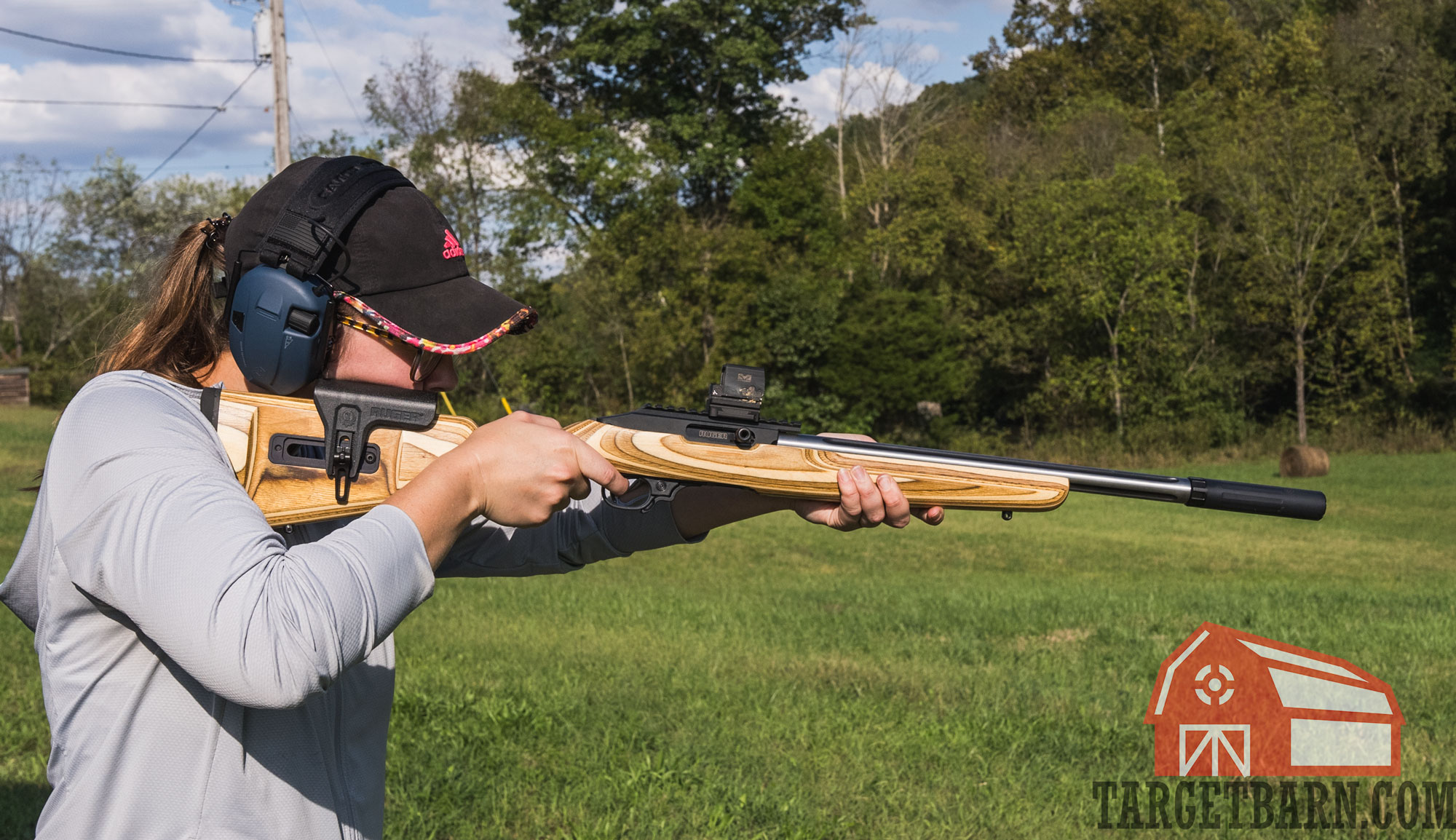 a woman shooting a suppressed rifle