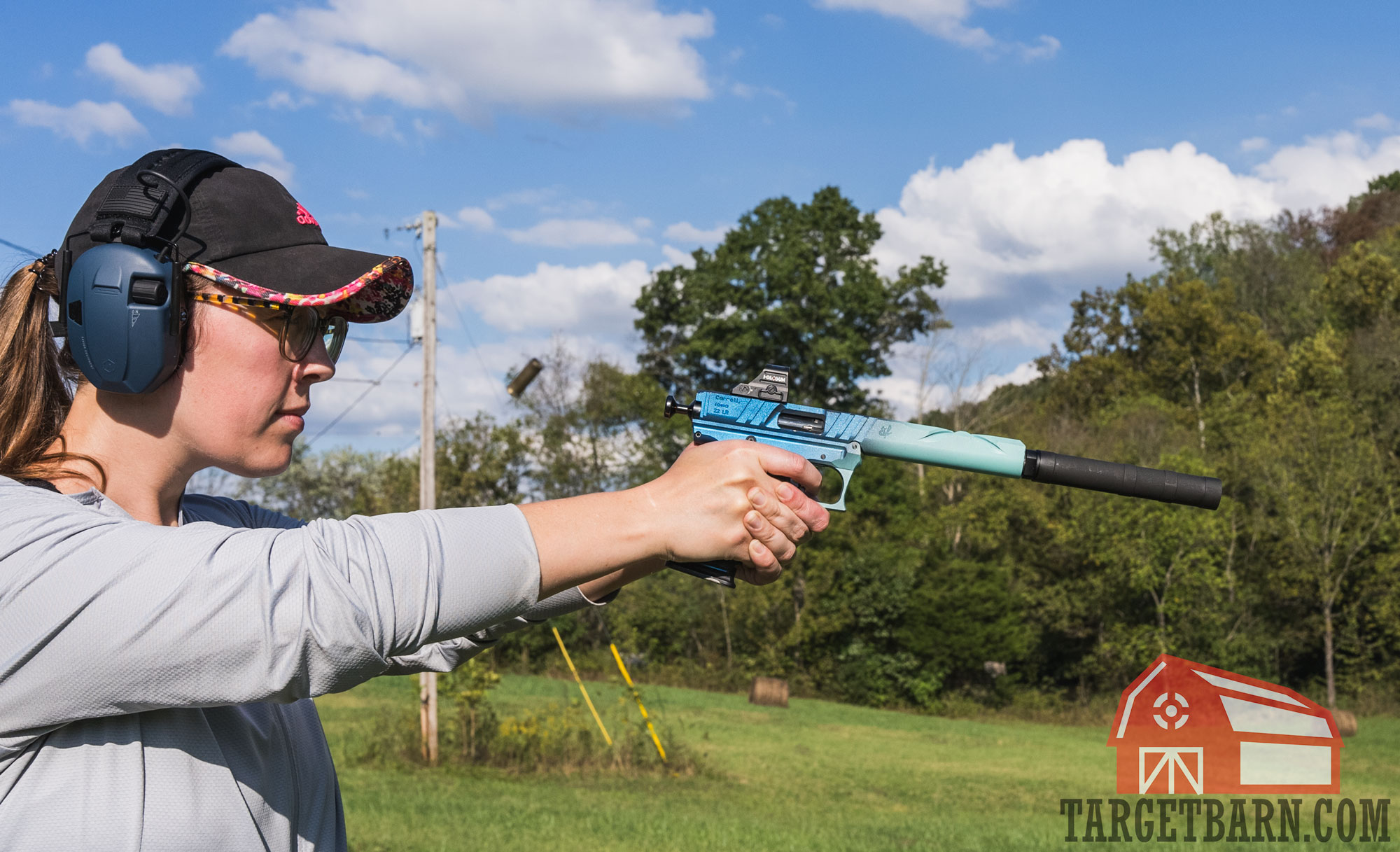 a woman shooting a volquartsen pistol mounted with a suppressor