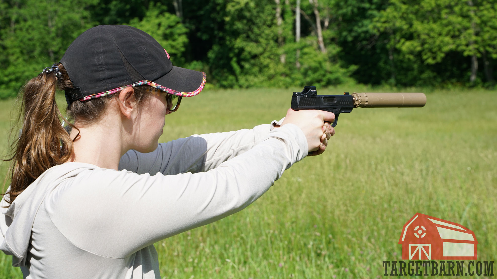 a woman shooting a suppressed 9mm handgun at the range